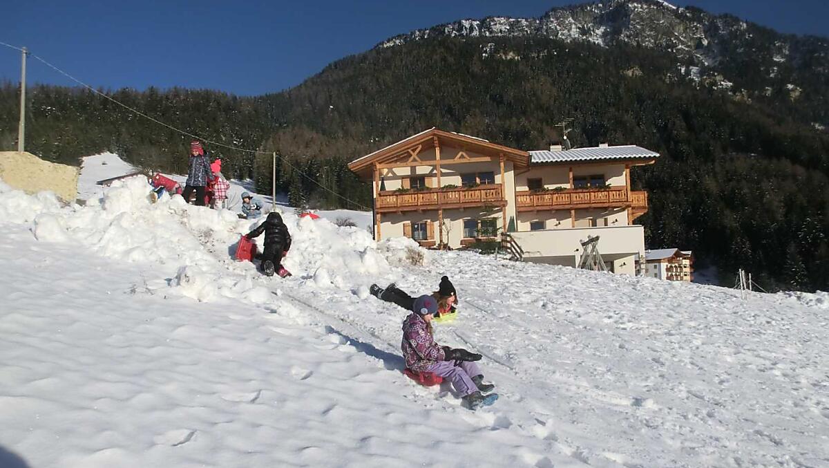 Kinderen glijden over de sneeuw en bouwen sneeuwkastelen