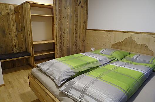 Slaapkamer met in glas gelaserde foto van de Schlern en inloopkast in vakantiewoning "Schmetterling"