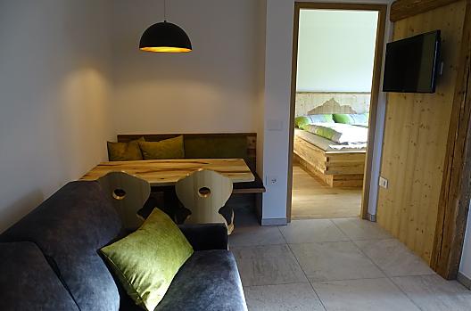 Woon- en eetruimte in vakantiewoning "Schmetterling", de bank kan naar wens worden uitgeschoven tot een bed van 120x190 cm.