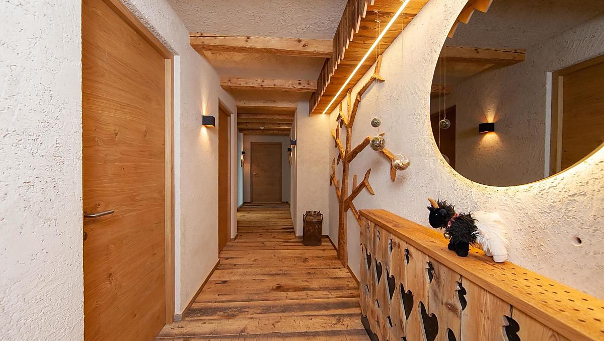 Ingangsgebied naar de vakantiewoningen: houten vloer, plafondbalken, houten hek en een boom gemaakt van het hout van onze oude schuur.