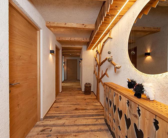 Ingangsgebied naar de vakantiewoningen: houten vloer, plafondbalken, houten hek en een boom gemaakt van het hout van onze oude schuur.