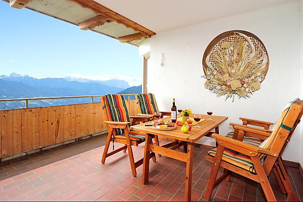 Große Balkonterrasse mit Hollywoodschaukel, Liegestühlen und großem Tisch mit Stühlen.
