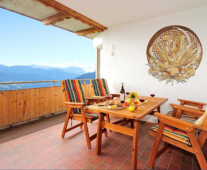 Große Balkonterrasse mit Hollywoodschaukel, Liegestühlen und großem Tisch mit Stühlen.