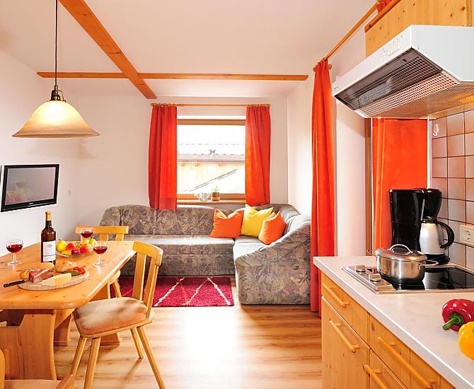 Wohnraum mit Küche mit direktem Zugang zur großen Balkonterrasse.