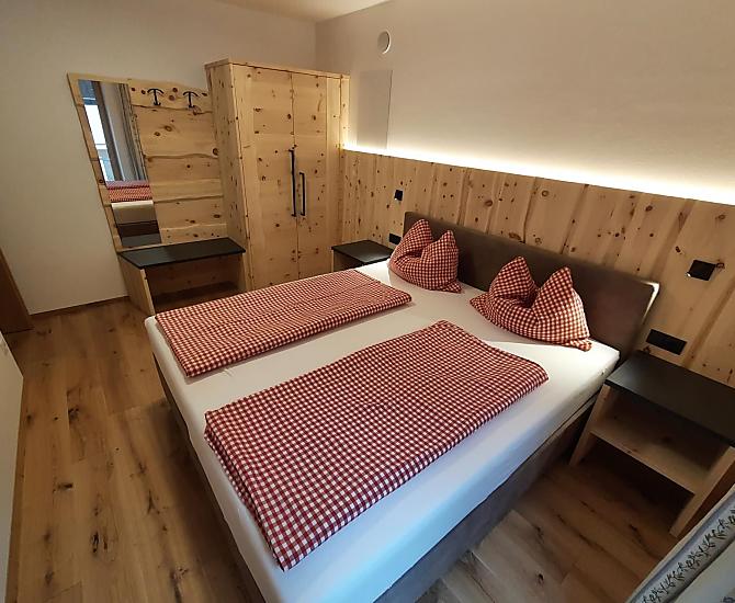 Doppelbettzimmer aus eigenem Zirbenholz kombiniert mit kuscheligem Boxspringbett