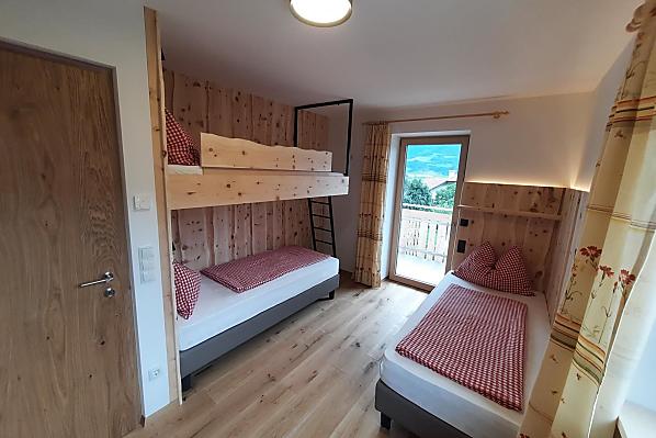 Mehrbettzimmer aus Zirbe mit zwei Einzelbetten und einem Stockbett. Die Einzelbetten kann man bei Bedarf zu einem Doppelbett zusammenfügen.