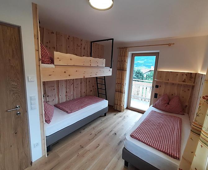 Mehrbettzimmer aus Zirbe mit zwei Einzelbetten und einem Stockbett. Die Einzelbetten kann man bei Bedarf zu einem Doppelbett zusammenfügen.