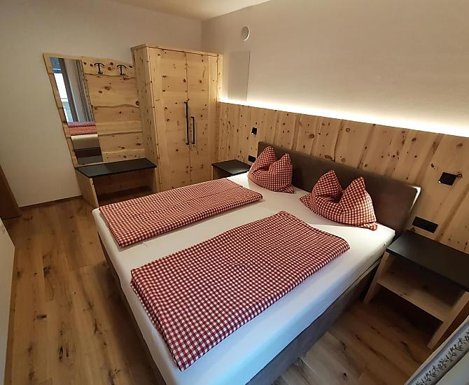 Doppelbettzimmer aus eigenem Zirbenholz kombiniert mit kuscheligem Boxspringbett