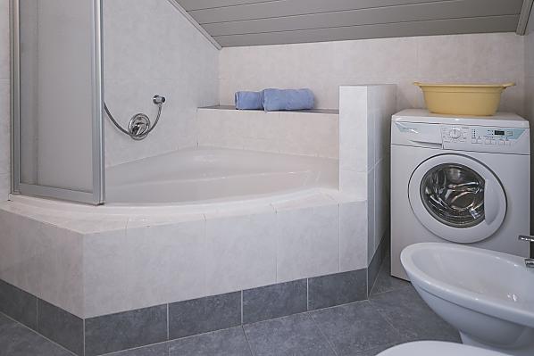 Badezimmer mit Eckbadewanne und Waschmaschine
