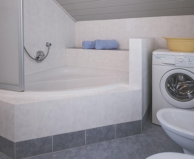 Badezimmer mit Eckbadewanne und Waschmaschine