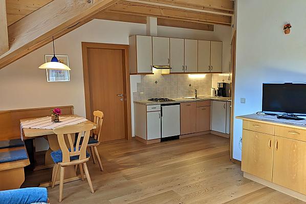 Wohnraum mit gemütlicher Sitzecke und komplett eingerichtetem Küchenblock mit Spülmaschine, Kaffeemaschine, Wasserkocher, Toaster.