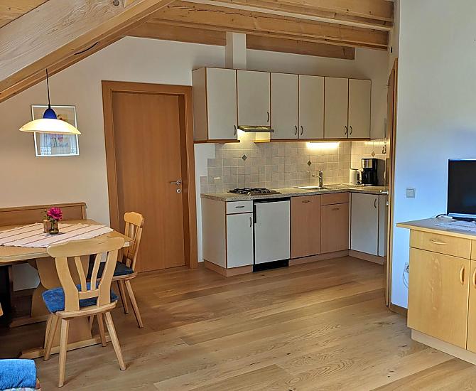 Wohnraum mit gemütlicher Sitzecke und komplett eingerichtetem Küchenblock mit Spülmaschine, Kaffeemaschine, Wasserkocher, Toaster.