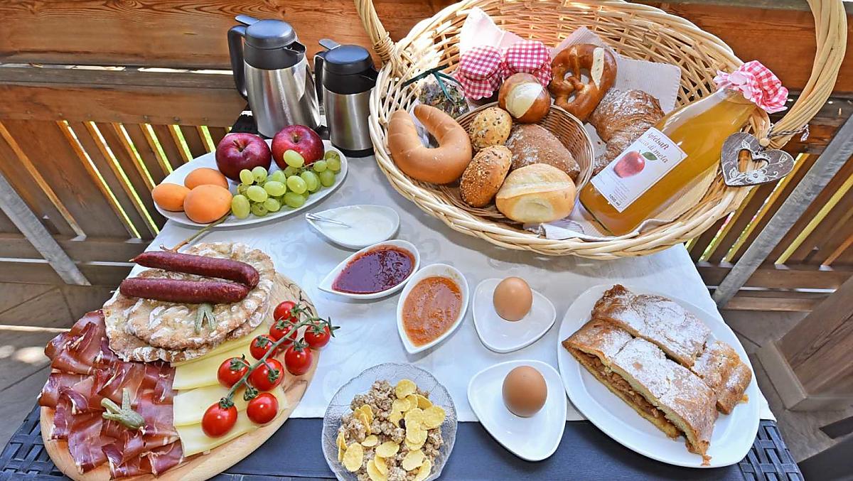 Ontbijt met zelfgemaakte jam en sappen van eigen fruit, verse apfelstrudel en spekplakjes met kaas uit de streek.