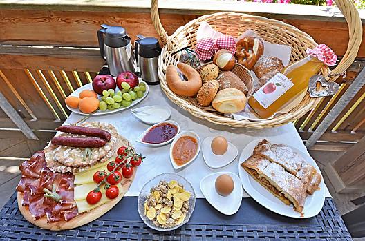 Ontbijt met zelfgemaakte jam en sappen van eigen fruit, verse apfelstrudel en spekplakjes met kaas uit de streek.