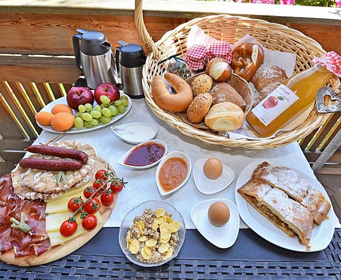 Ontbijt met zelfgemaakte jam en sappen van eigen fruit, verse apfelstrudel en spekplakjes met kaas uit de streek.