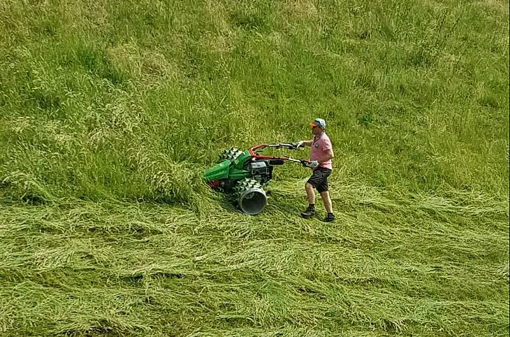 Gastheer en boer Herbert maait het gras op onze steile bergweiden met de prikrolmaaier.