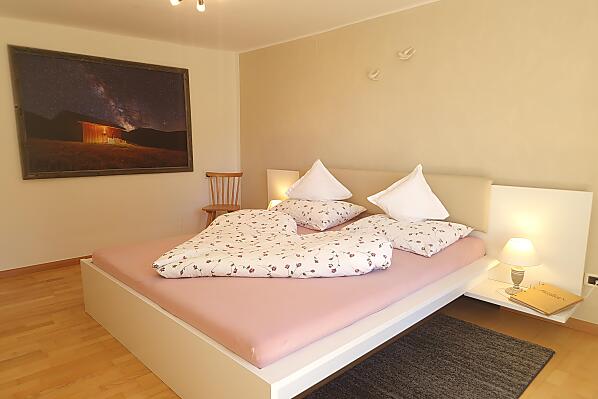 Gemütliches Schlafzimmer mit Zugang zum Balkon und Blick in den Bauerngarten und auf die Berge.