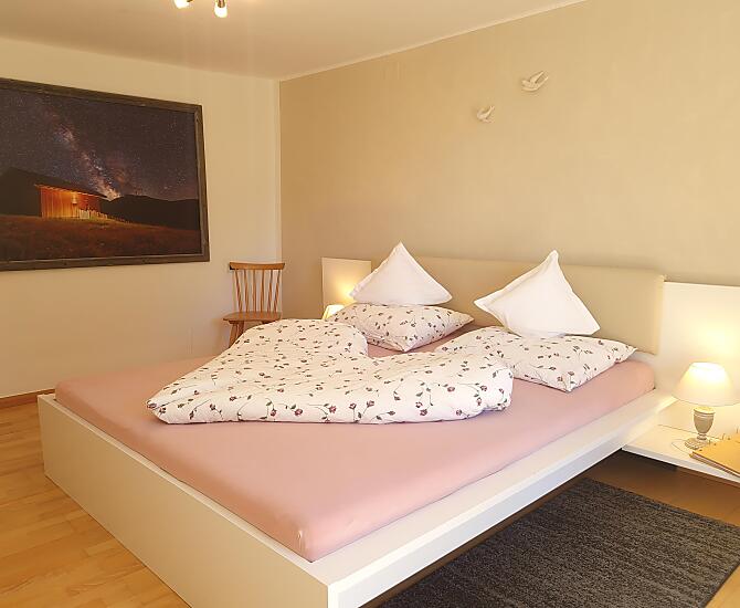 Gemütliches Schlafzimmer mit Zugang zum Balkon und Blick in den Bauerngarten und auf die Berge.